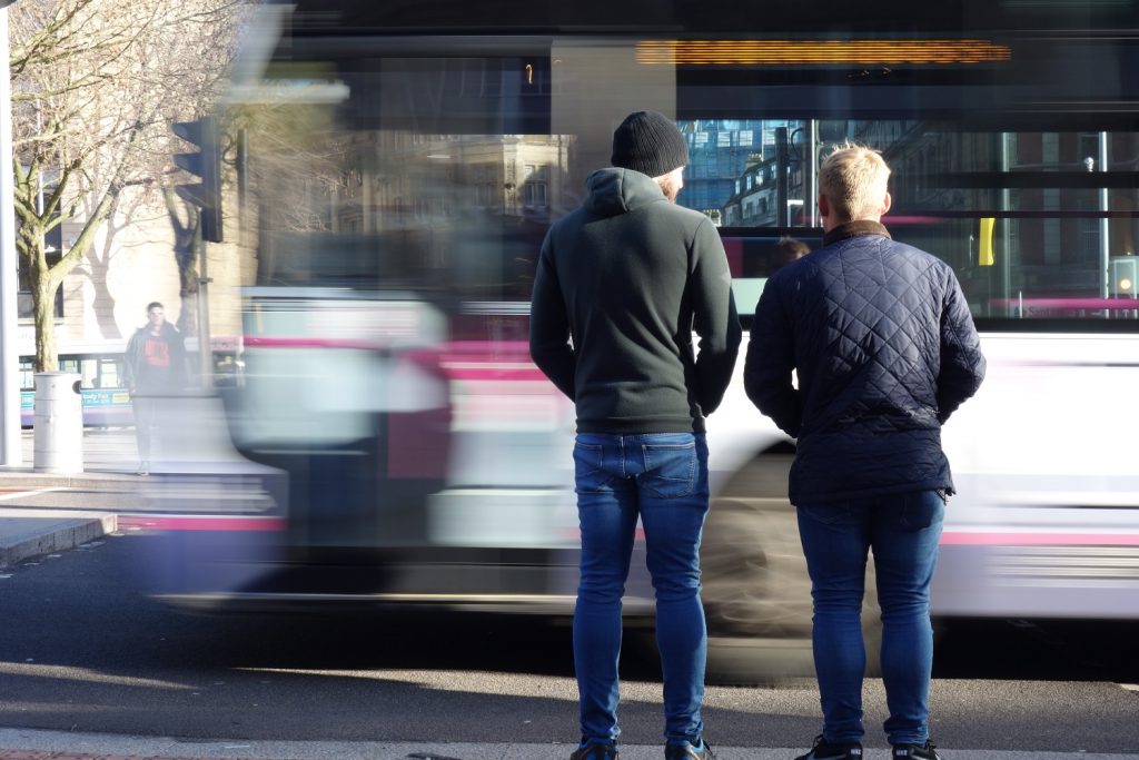 Bristol city centre after metrobus construction work - bus blurred passing two people standing on pavement