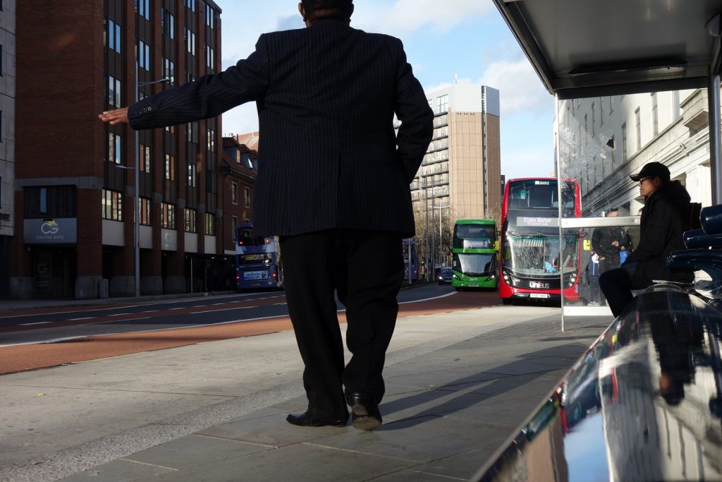 Bristol city centre after metrobus construction work - person at bus stop stretching arm to request bus to stop